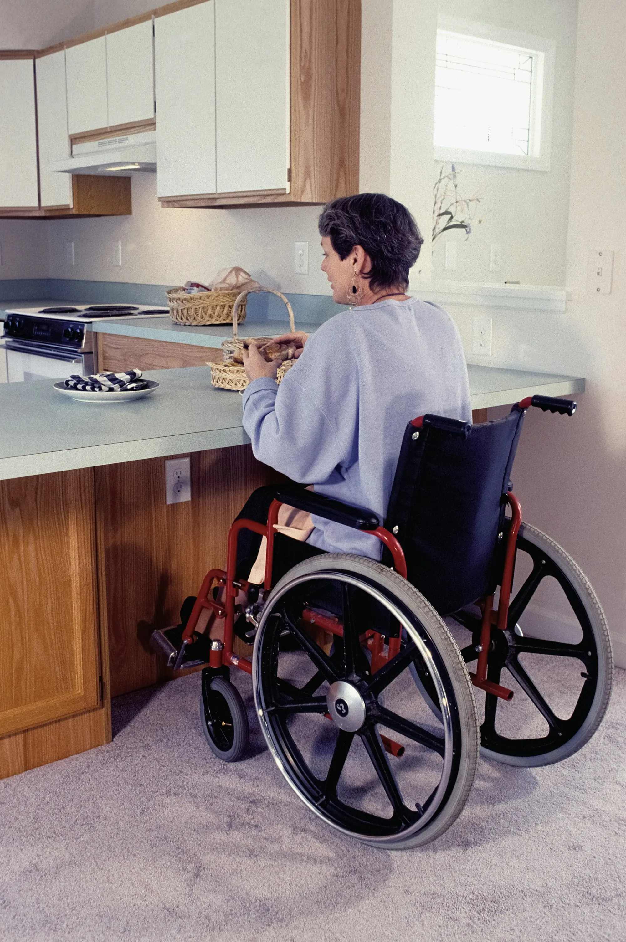 A woman using a wheelchair in her own kitchen