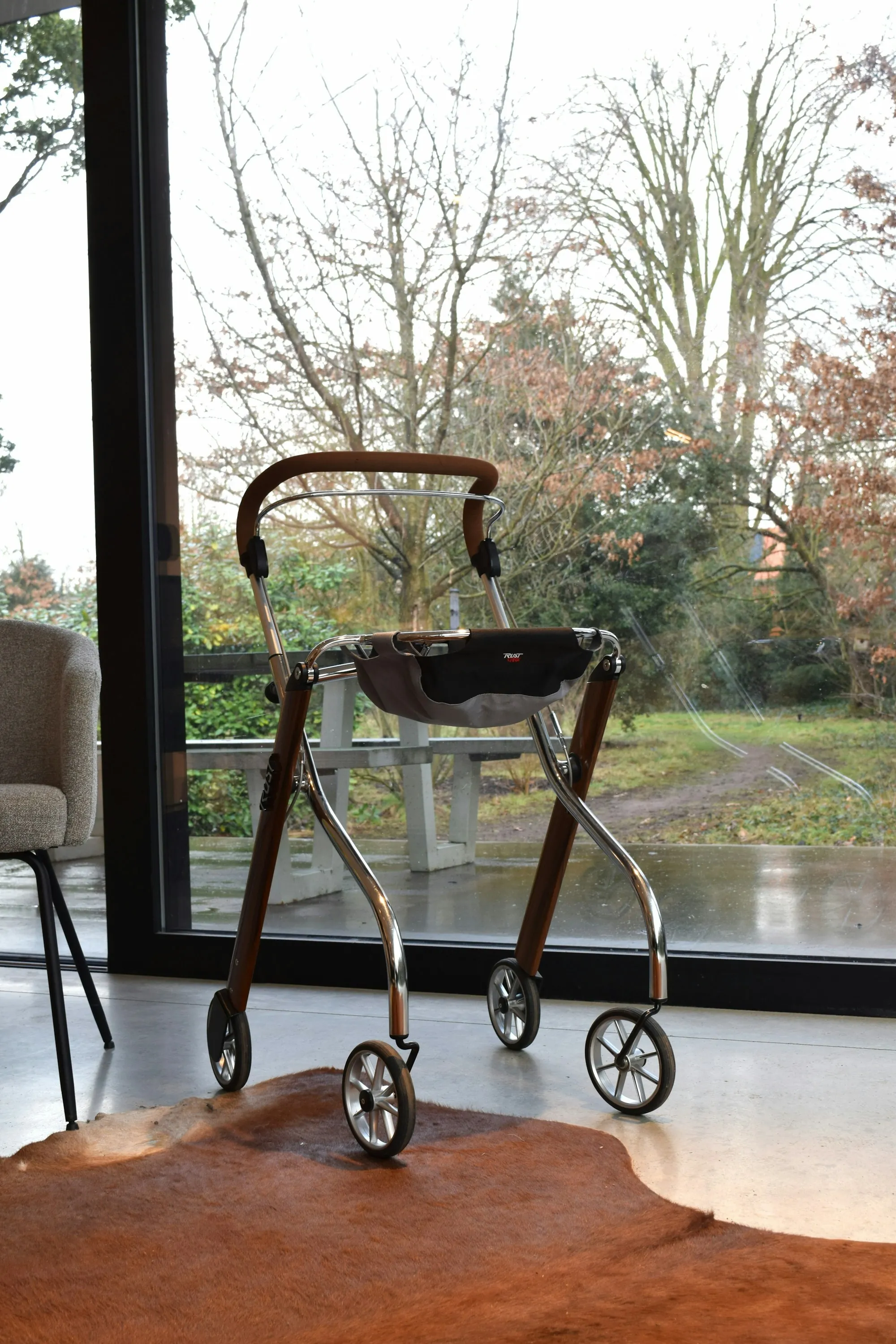 A wheeled walking frame indoors beside a large window