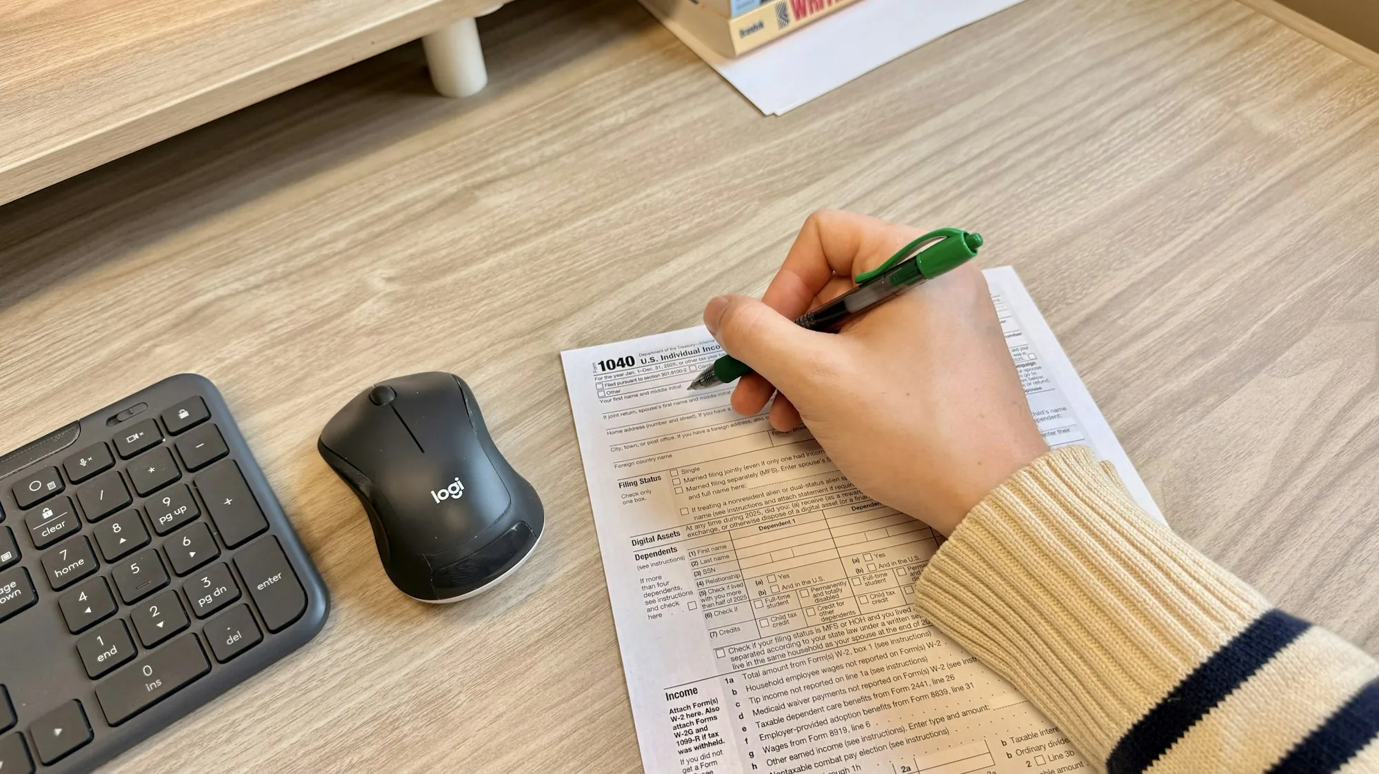 A hand writing on a document at a desk