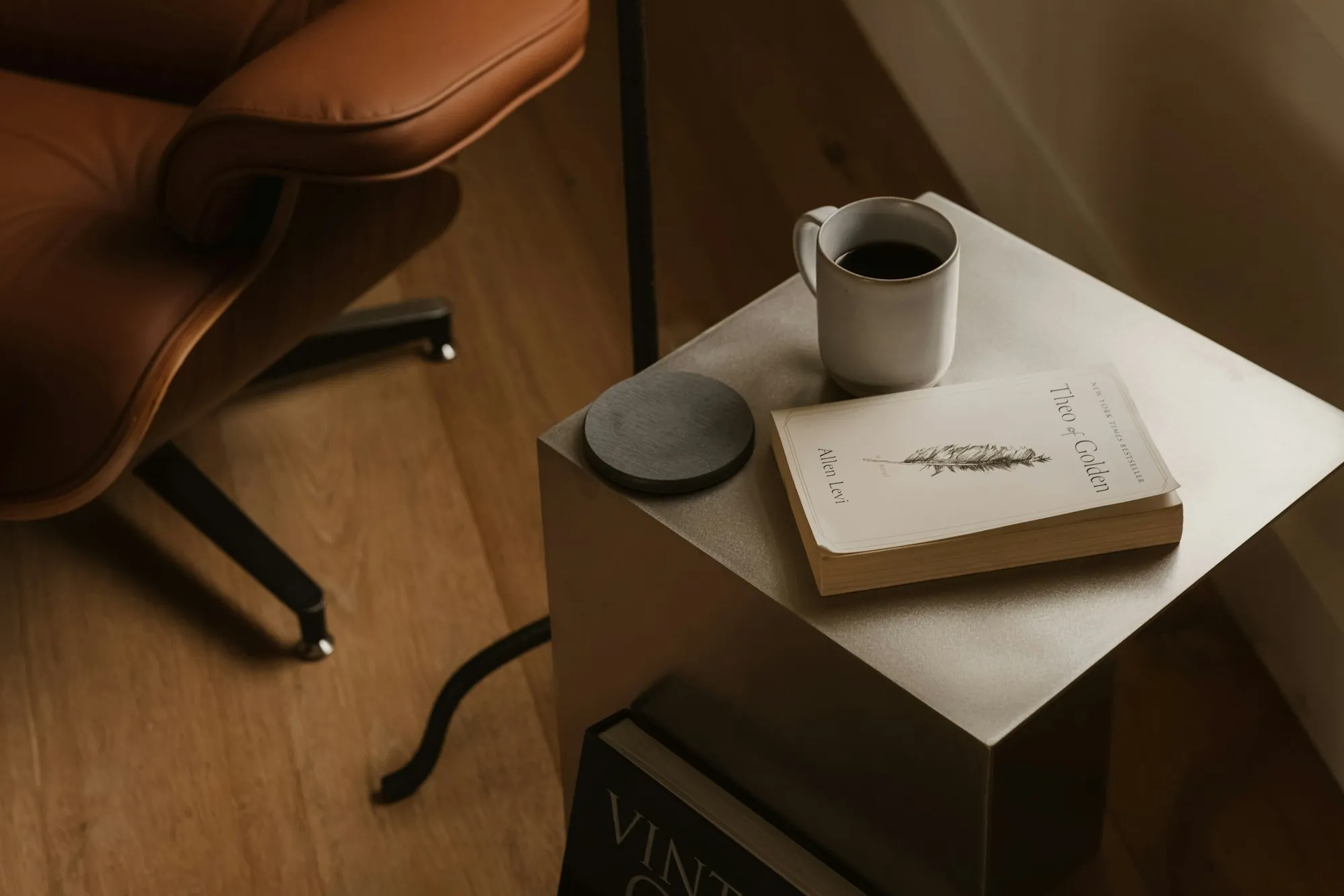 A book and a mug on a side table beside an armchair