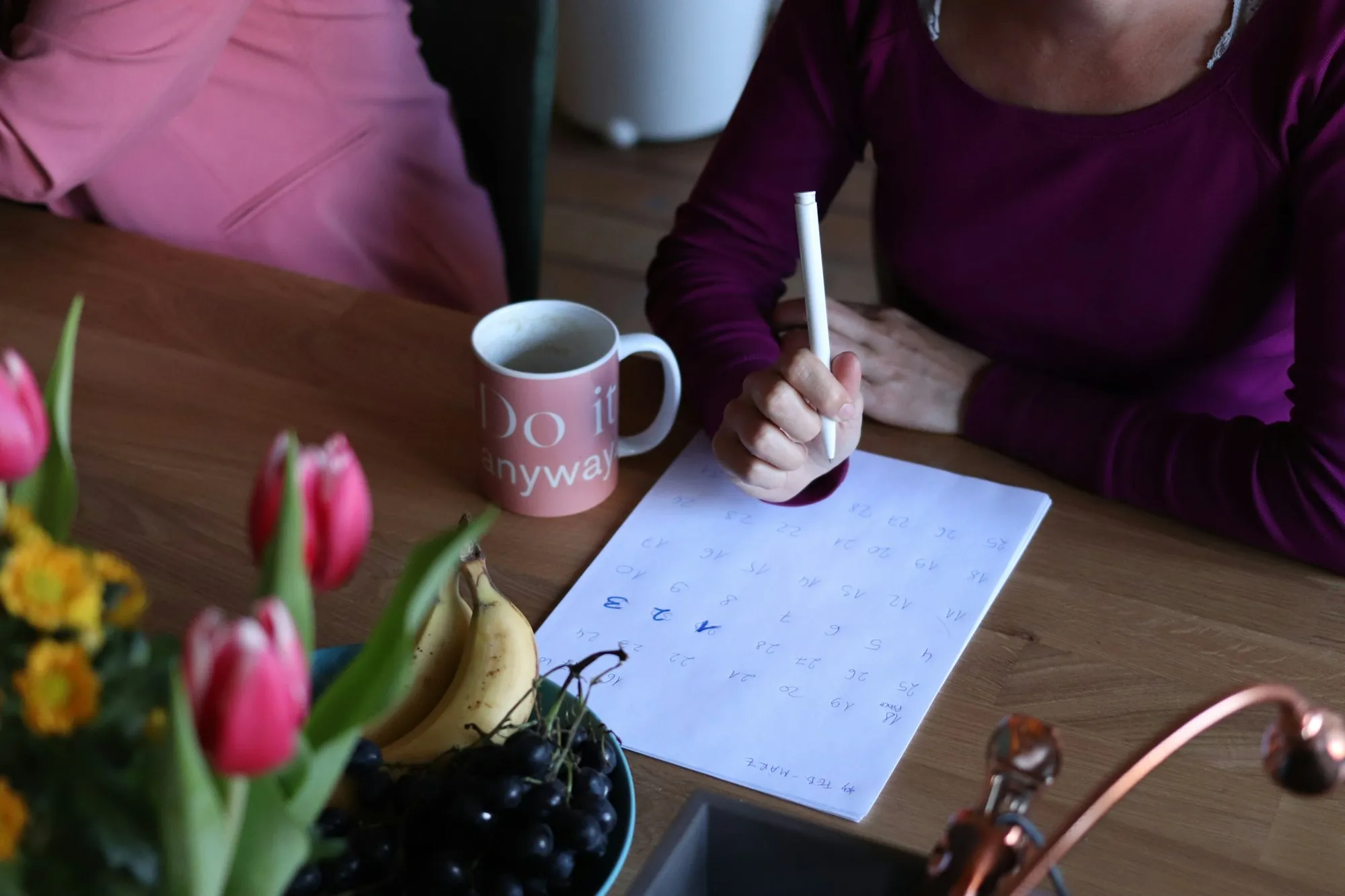 A hand filling in a printed form at a desk